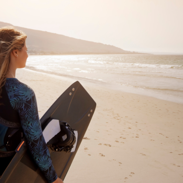 kvinde står på en strand med et af hende mange kiteboards